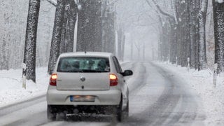 Ein Auto fährt eine verschneite Straße entlang | So fahrt ihr sicher auf glatten Straßen