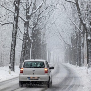 Ein Auto fährt eine verschneite Straße entlang | So fahrt ihr sicher auf glatten Straßen