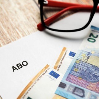 Abo als Weihnachtsgeschenk: Ein weißer Brief mit Überschrift Abo neben einer Brille und Euro Geldscheinen | Abonnements als Weihnachtsgeschenke: Das müsst ihr über Abos und Gutscheine wissen