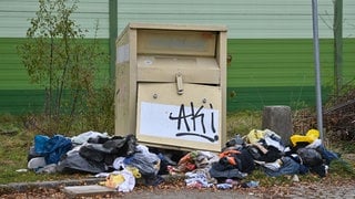 Demolierter Altkleidercontainer, Kleidung liegt auf dem Boden | Warum gibt es immer wieder Ärger mit Altkleidercontainern?