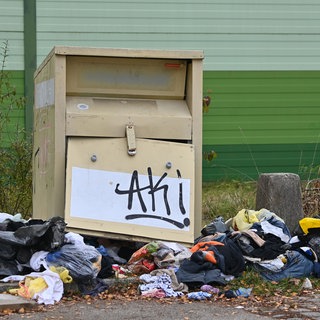 Demolierter Altkleidercontainer, Kleidung liegt auf dem Boden | Warum gibt es immer wieder Ärger mit Altkleidercontainern?