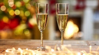 Zwei Sektgläser auf einem festlich geschmückten Tisch | Das passende Getränk zum Fest: Das müsst ihr bei der Auswahl von Sekt und Champagner beachten