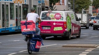 Ein Flink Kurier auf dem Fahrrad und ein Fahrzeug von Flaschenpost fahren auf einer Straße | Darauf solltet ihr bei Lieferdiensten für Lebensmittel achten