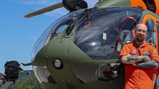 Dennis Prosser, Lufretter bei der Bundeswehr steht vor dem Hubschrauber. Er ist zu Gast in SWR1 Leute. | Bundeswehr-Luftretter Dennis Prosser hat Menschen bei der Ahrtal-Flutkatastrophe gerettet