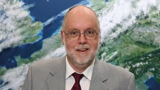 Prof. Roland Potthast, beim Deutschen Wetterdienst, steht vor einer Wetterkarte. Er arbeitet für den Deutschen Wetterdienst. In SWR1 Leute erklärt er, wie das Wetter vorhergesagt wird und welche Chancen er für die Wetterprognose mit KI sieht.