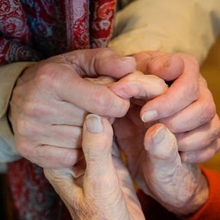 Hände einer alten Frau werden gehalten