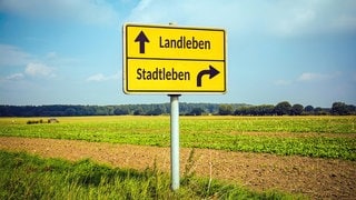 Ein Schild zeigt "Stadtleben" und "Landleben".