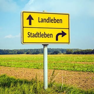 Ein Schild zeigt "Stadtleben" und "Landleben".