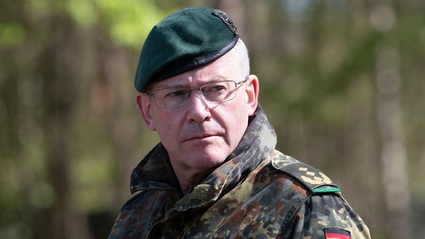 André Bodemann, Generalleutnant, steht in Camouflage-Uniform und Barett auf dem Truppenuebungsplatz in Munster