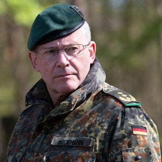 André Bodemann, Generalleutnant, steht in Camouflage-Uniform und Barett auf dem Truppenuebungsplatz in Munster