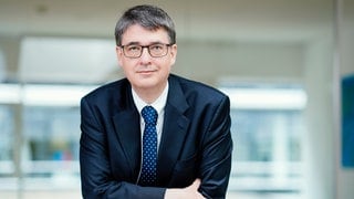 Prof. Michael Baumann, Präsident des Deutsches Krebsforschungszentrums, lehnt mit verschränkten Armen auf einem Tisch.  Krebs galt früher als unheilbar, dann kamen Chemotherapie und Strahlenbehandlung. Welche neuen Methoden der Krebstherapie gibt es? Wir sprechen in SWR1 Leute darüber mit Prof. Michael Baumann.