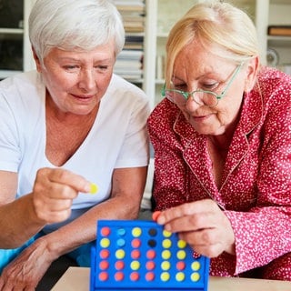 Zwei Senioren spielen konzentriert "Vier gewinnt" in der Freizeit als Gehirnjogging und Denksport.  In SWR1 Leute sprechen wir mit Prof. Frank Jessen über seine Forschung an Früherkennung und Vorbeugung von Alzheimer: Ein aktiver Lebensstil kann bis zu 40 Prozent des Demenz Risikos beeinflussen.