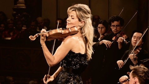 Anne-Sophie Mutter, Stargeigerin, steht zwischen anderen Streichern und spielt Geige.