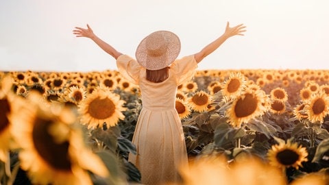 Eine glückliche Frau umgeben von Sonnenblumen.