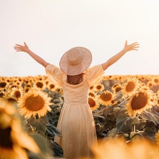 Eine glückliche Frau umgeben von Sonnenblumen.