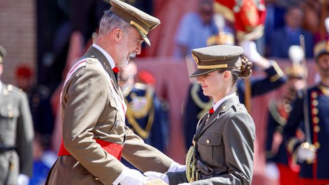 links steht lächelnd König Felipe in Uniform und überreicht seiner Tochter, die rechts in Uniform steht, eine Urkunde