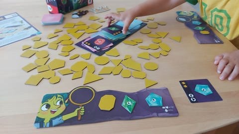 Eine Auslage von vielen gelben Pappplättchen in Edelstein-Formen: Das Brettspiel "Große kleine Edelsteine" ist von der Jury "Spiel des Jahres" nominiert zum "Kinderspiel des Jahres 2024".