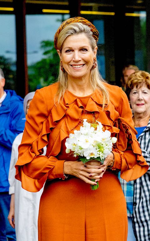 Königin Maxima trägt einen herbstlichen Look bei der Eröffnung der neuen Ambulanz der niederländischen Endometrioseklinik im Reiner de Graaf Krankenhaus und trägt einen Blumenstrauß aus weißen Blumen.