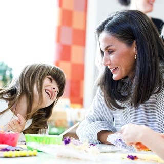 Königin Letizia sitzt neben einem Mädchen mit dunklen Haaren und lacht mit ihr. Letizia von Spanien nahm an der Eröffnung des Schuljahres 204425 in der Schule Placida Herranz am 11. September 2024 in Azuqueca de Henares in der Nähe von Guadalajara, Spanien, teil.