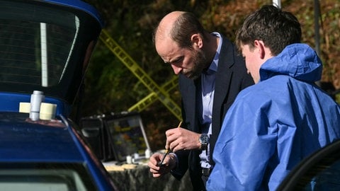 Prinz William steht an einem Auto und sucht mit Puder und Pinsel an einem gestellten Tatort nach Fingerabdrücken. Der britische Thronfolger besuchte ein College in Südengland und ließ sich von Studenten die Arbeitsweise der Kriminaltechnik zeigen. 