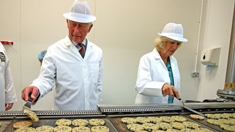 König Charles und Königin Camilla wenden walisische Kekse während ihres Rundgangs durch die Village Bakery in Wrexham.