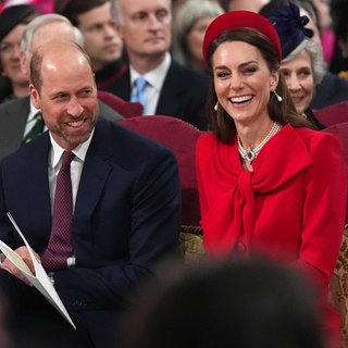 Die britische Prinzessin Kate von Wales lacht im roten Kleid und rotem Hut. Prinz William steht in blauem Anzug beim jährlichen Gottesdienst zum Commonwealth Day in der Westminster Abbey in London neben ihr.