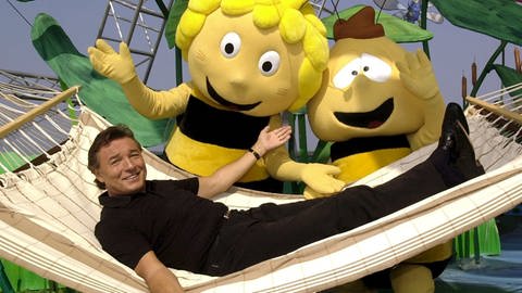 Karel Gott liegt in einer Hängematte neben den überdimensionalen Trickfilmfiguren "Biene Maja" und "Willi"
