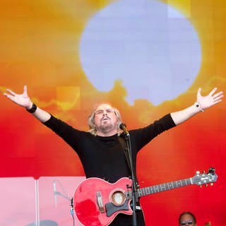 Barry Gibb von den Bee Gees tritt mit Gitarre und erhobenen Armen auf der Bühne auf