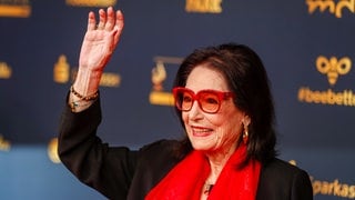 Nana Mouskouri kommt 2022 mit roter Brille zu der Verleihung des Medienpreises "Goldene Henne" in Leipzig.