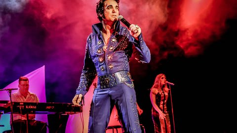 Der Darsteller des Musicals in einem blauen Elvis Kostüm auf der Bühne