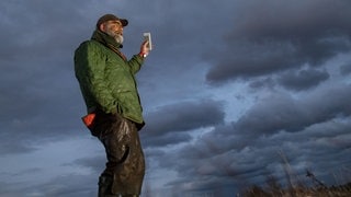 Das Hörspiel "Schwarzwald-Ranger" in schwäbischer Mundart: Ein Förster steht auf einer Anhöhe und streckt sein Handy in die Luft.