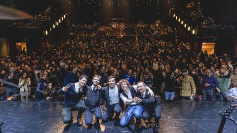 Die Musiker und Sänger der Simon and Garfunkel Story knien mit dem Rücken zum Publikum