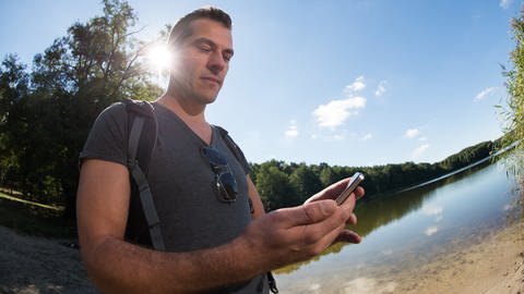 Wanderer orientiert sich mit Hilfe seines Smartphones - länger Strom  Akku 
