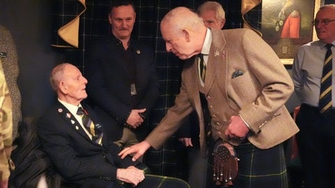 König Charles III. besucht ein Museum in Schottland und trifft einen 99-jährigen Weltkriegs-Veteranen. Bei dem Treffen trägt er stilecht einen Kilt, das traditionsreiche Kleidungsstück der Schotten.