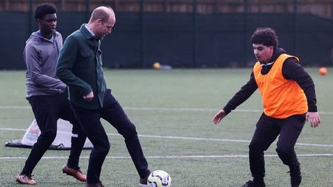 Prinz William spielt Fußball gegen zwei Jugendliche bei einem Besuch eines Gemeinschaftszentrums in Liverpool.