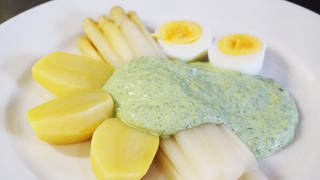weißer Teller mit Stangenspargel mit grüner Soße, dazu Kartoffeln und zwei hartgekochte Eier