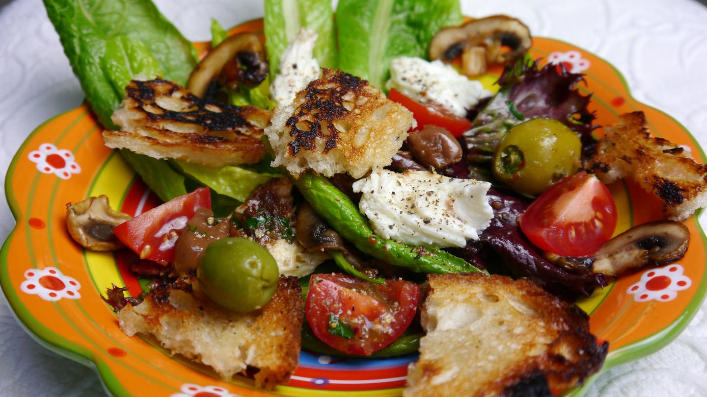 bunter Teller mit Salat mit Tomaten, Oliven und geröstetem Brot
