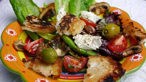 bunter Teller mit Salat mit Tomaten, Oliven und geröstetem Brot