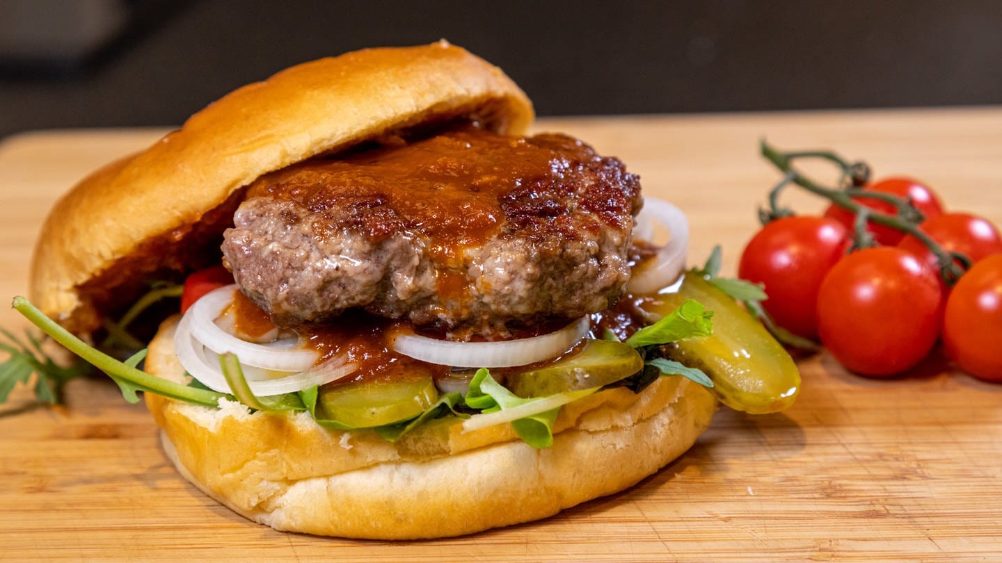 Rezept für Burger Patties: Der fertige Hamburger auf einem Holzbrett angerichtet.