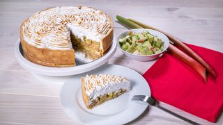 Der Rhabarberkuchen auf einem Mürbteigboden mit einer Haube aus Baiser ist auf dem Kuchentafel eine wahre Pracht.