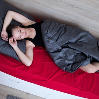 Einschlafen bei Hitze: Eine Frau liegt im Bett und kann nicht schlafen