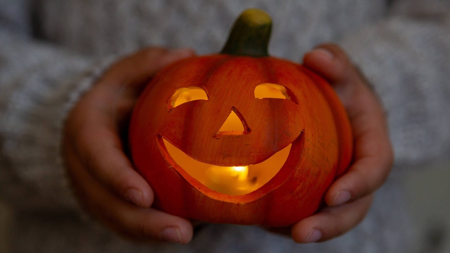 Halloween-Deko-Trends 2023: ein lächelnder Kürbis mit Gesicht und Kerze
