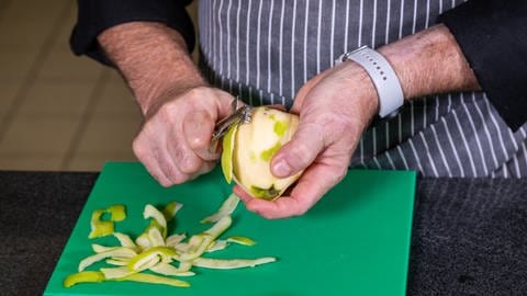 Eine Birnenquitte wird mit einem Obstschäler geschält