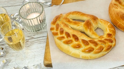 Neujahrsbrezel mit Rezept: Backen fürs neue Jahr. Zwei Brezeln sind neben gefüllten Sektgläsern angerichtet.