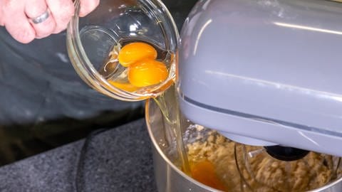 Die rohen Eier werden dem Teig für die Rhabarberschnitte zugegeben. Danach kommen laut Rezept ganz einfach die weiteren Zutaten hinzu.