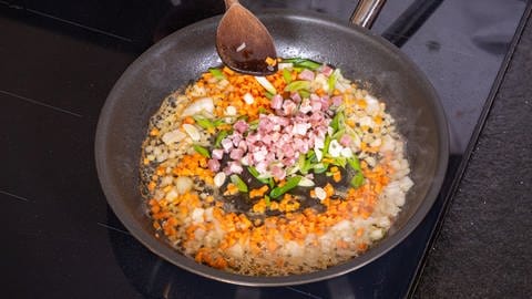 Schweinemedaillons im Speckmantel in fruchtiger Soße: Schalotten, Speck, Knoblauch, Karotte und Lauch in der Pfanne anschwitzen.