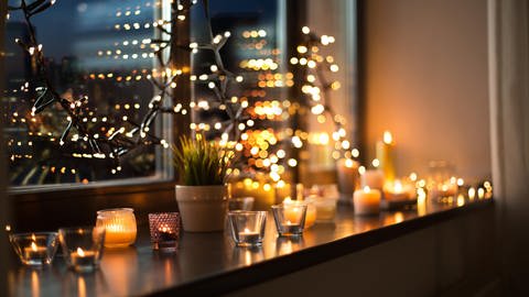 Weihnachtsdeko mit Lichterkette und Kerzen auf der Fensterbank.