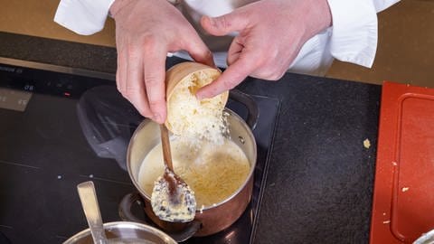 Gnocchi mit leckerer Soße aus Parmesan und weiteren Zutaten: In den Topf mit Schalotten und Brühe wird der Parmesan hinzugegeben.