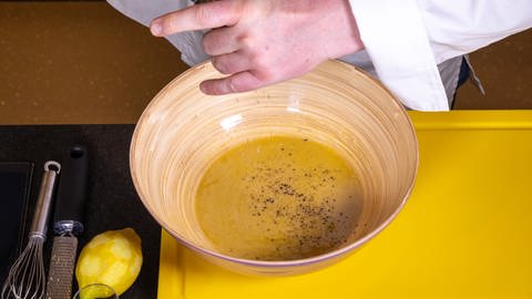 Der Nizzasalat mit Ei und Thunfisch bekommt durch das original Dressing den richtigen Kick. Dieses beinhaltet unter anderem Senf, Weißweinessig und Olivenöl und wird hier in einer Schüssel zubereitet.