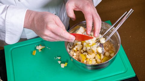 Die kleingeschnittenen Birnenwürfel werden dem Joghurtdressing und dem Sauerkraut hinzugegeben.